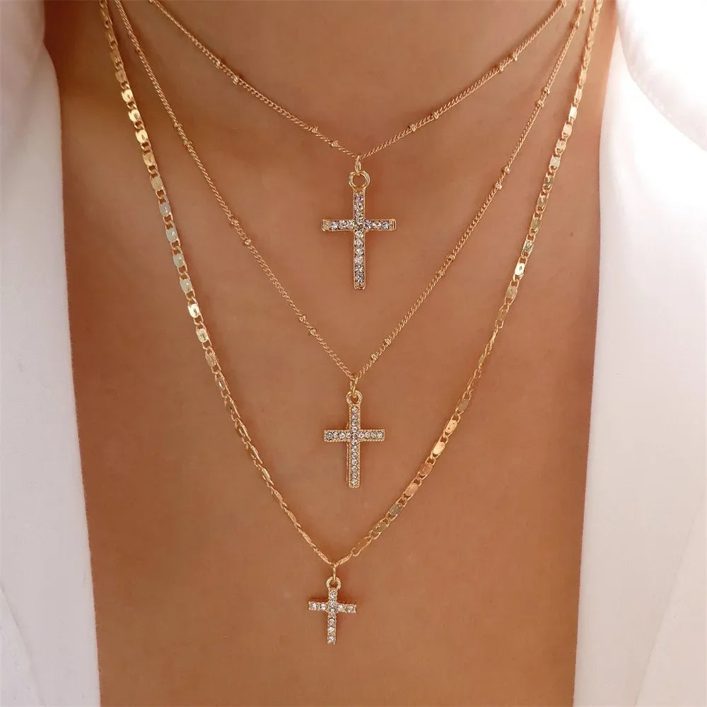 Woman wearing three layered gold-tone necklaces with clear stone-accented cross pendants