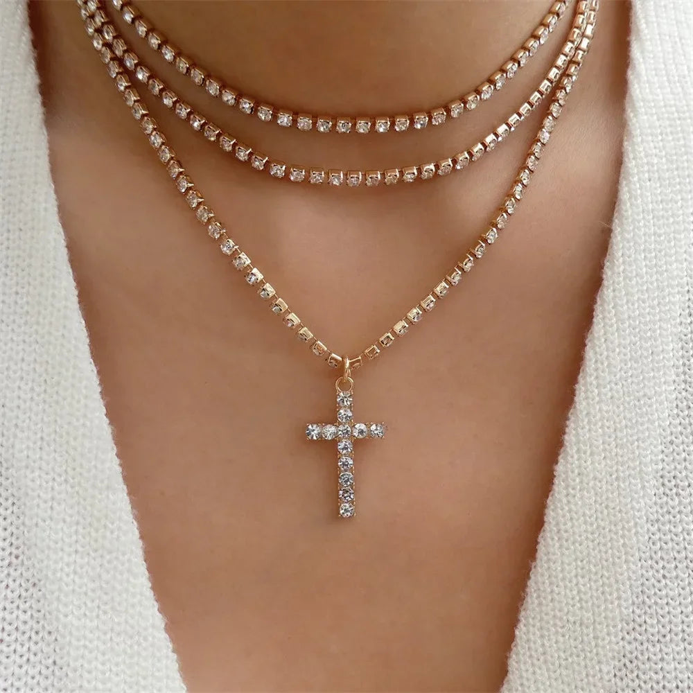 Woman wearing layered gold-tone rhinestone necklaces with a crystal cross pendant