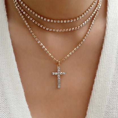 Woman wearing layered gold-tone rhinestone necklaces with a crystal cross pendant