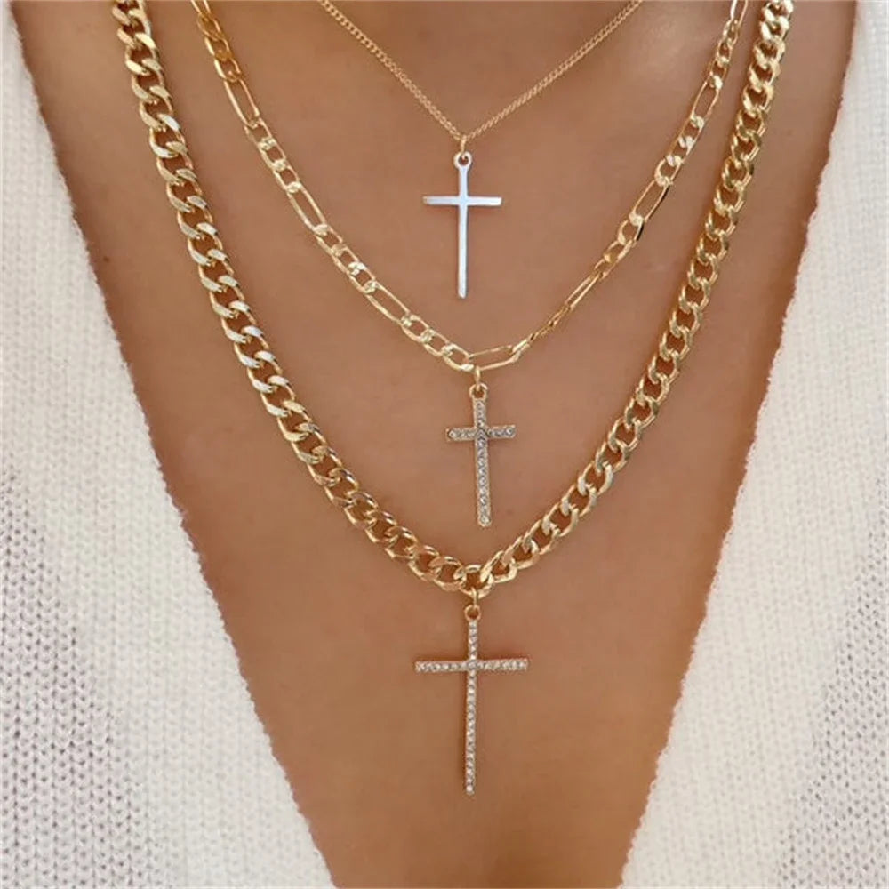 Woman wearing layered gold-tone chain necklaces with three cross pendants, including crystal-accented crosses